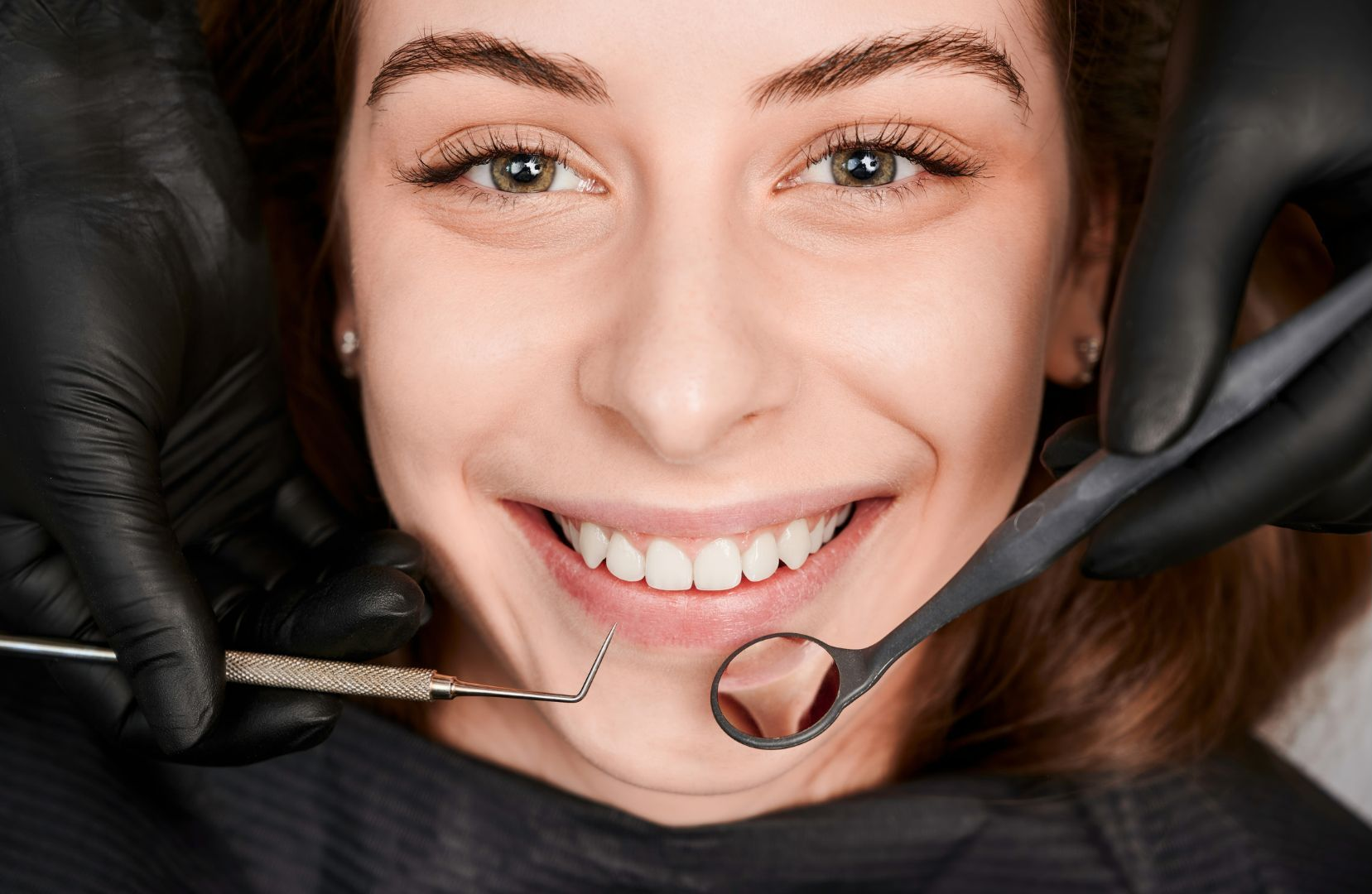 Woman at the dentist smiling, dental tools in view.