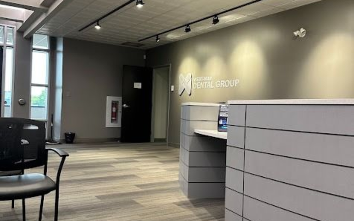 Two people in teal scrubs review a computer screen, one pointing. Light office setting.