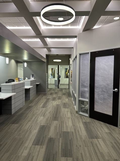 Modern office hallway with wood-look flooring, reception desk, and a frosted glass door.