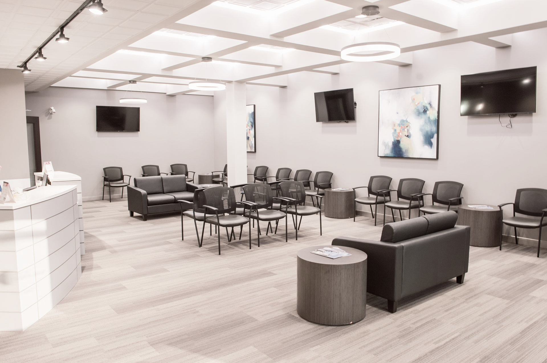 Woman in blue scrubs smiles while sitting at a desk with a computer and keyboard.