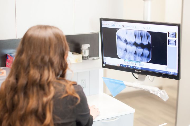 Woman looking at dental x-ray on a monitor in a dentist's office.