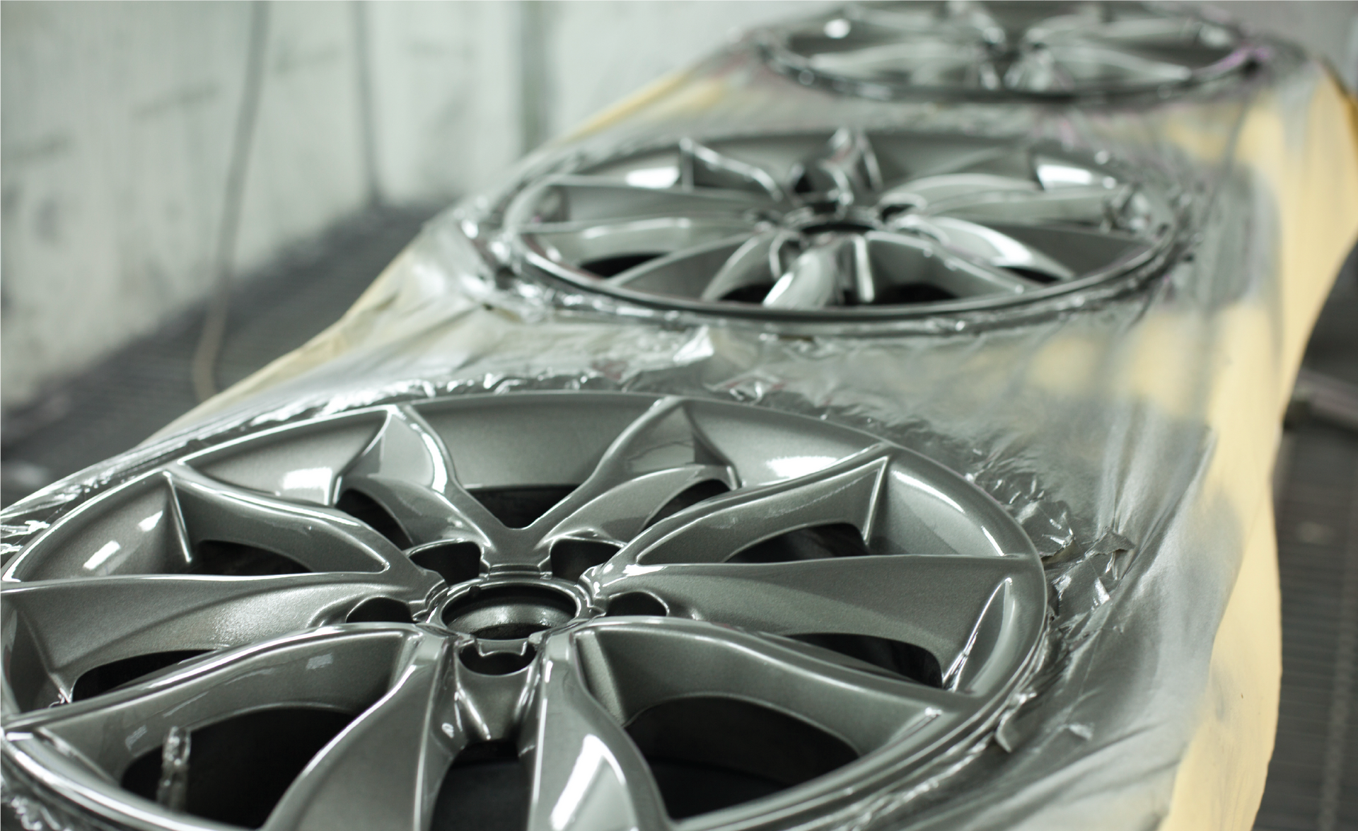 A row of silver wheels are covered in plastic wrap.