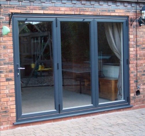 Black-framed sliding glass patio doors set in a brick wall, with curtains visible inside.