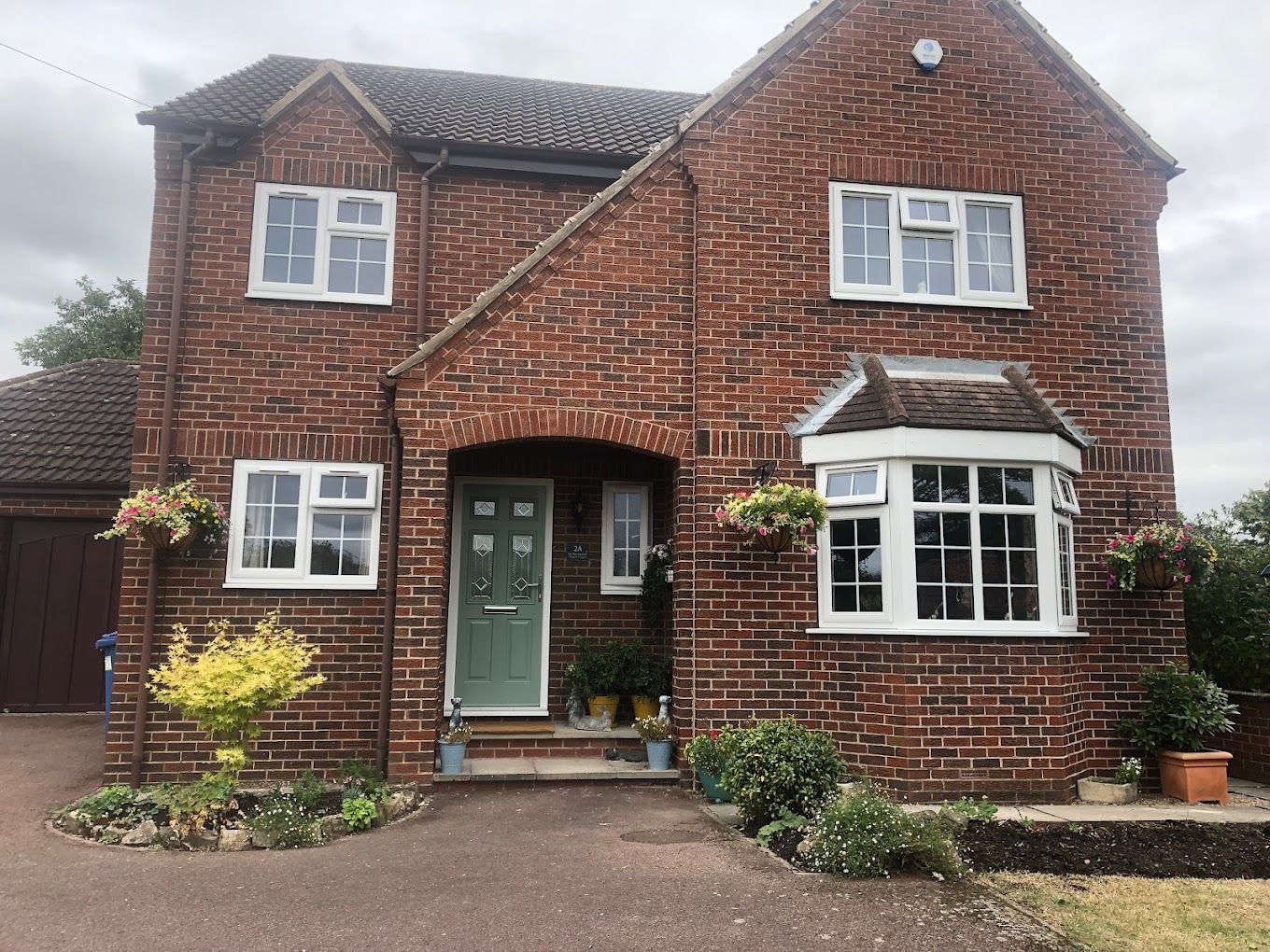 A brick house with a green door and white windows