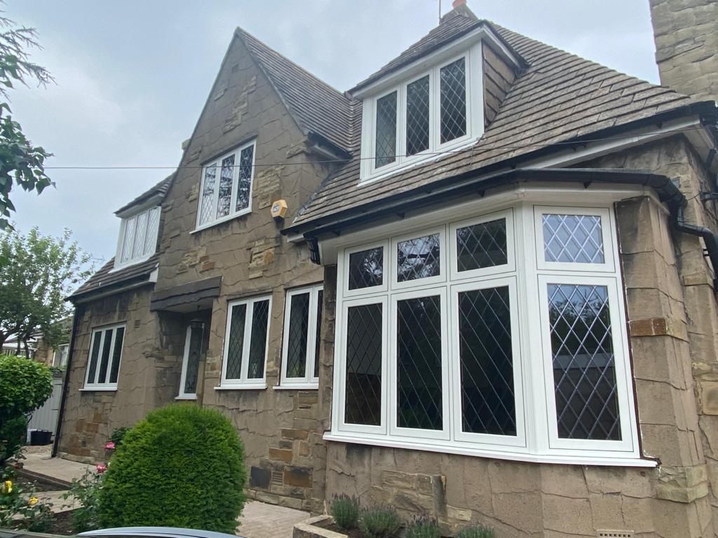 Stone house with white bay windows and a pitched tiled roof, viewed from the front garden.