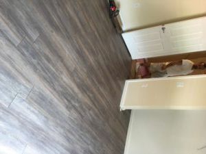 A person is laying on a wooden floor in a room.