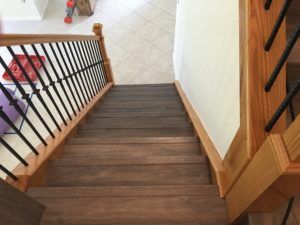 A wooden staircase with a metal railing leading up to the second floor of a house.
