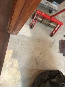 A red roller is sitting on the floor next to a door.