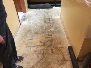 A person is standing in a hallway with a dirty floor.