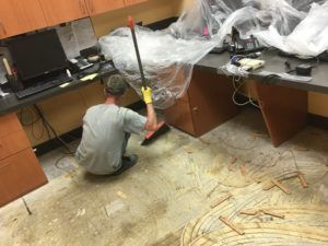 A man is cleaning the floor of an office with a mop.