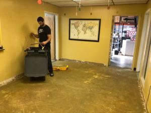 A man is cleaning the floor of a room with a mop.