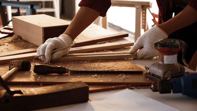 A man is laying a tile floor in a room.