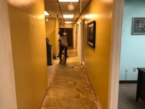 A man is standing in a hallway with yellow walls.