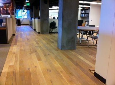 A hallway with a wooden floor and concrete pillars