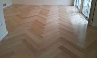 A wooden floor with a herringbone pattern in a living room.