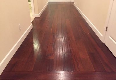 A hallway with hardwood floors and white trim in a house.