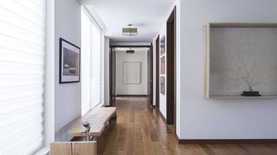 A long hallway with a wooden bench and a window.