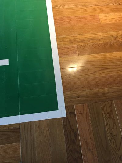 A green basketball court with a white line on a wooden floor.