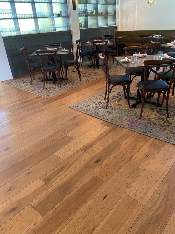 A restaurant with wooden floors and tables and chairs.