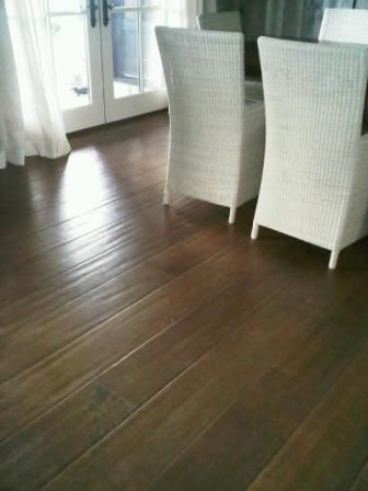 Two white wicker chairs are sitting on a wooden floor in a living room.