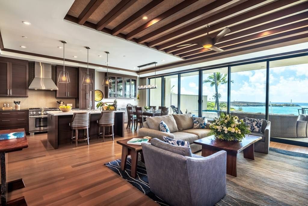 A living room filled with furniture and a kitchen with a view of the ocean.
