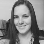 A woman with long hair is smiling in a black and white photo.