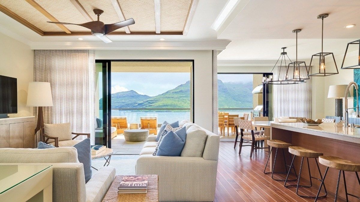 A living room with a couch , table , chairs and a ceiling fan.