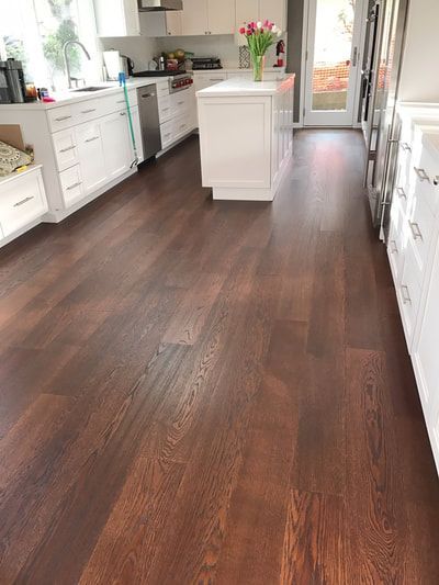 A kitchen with a wooden floor and white cabinets.