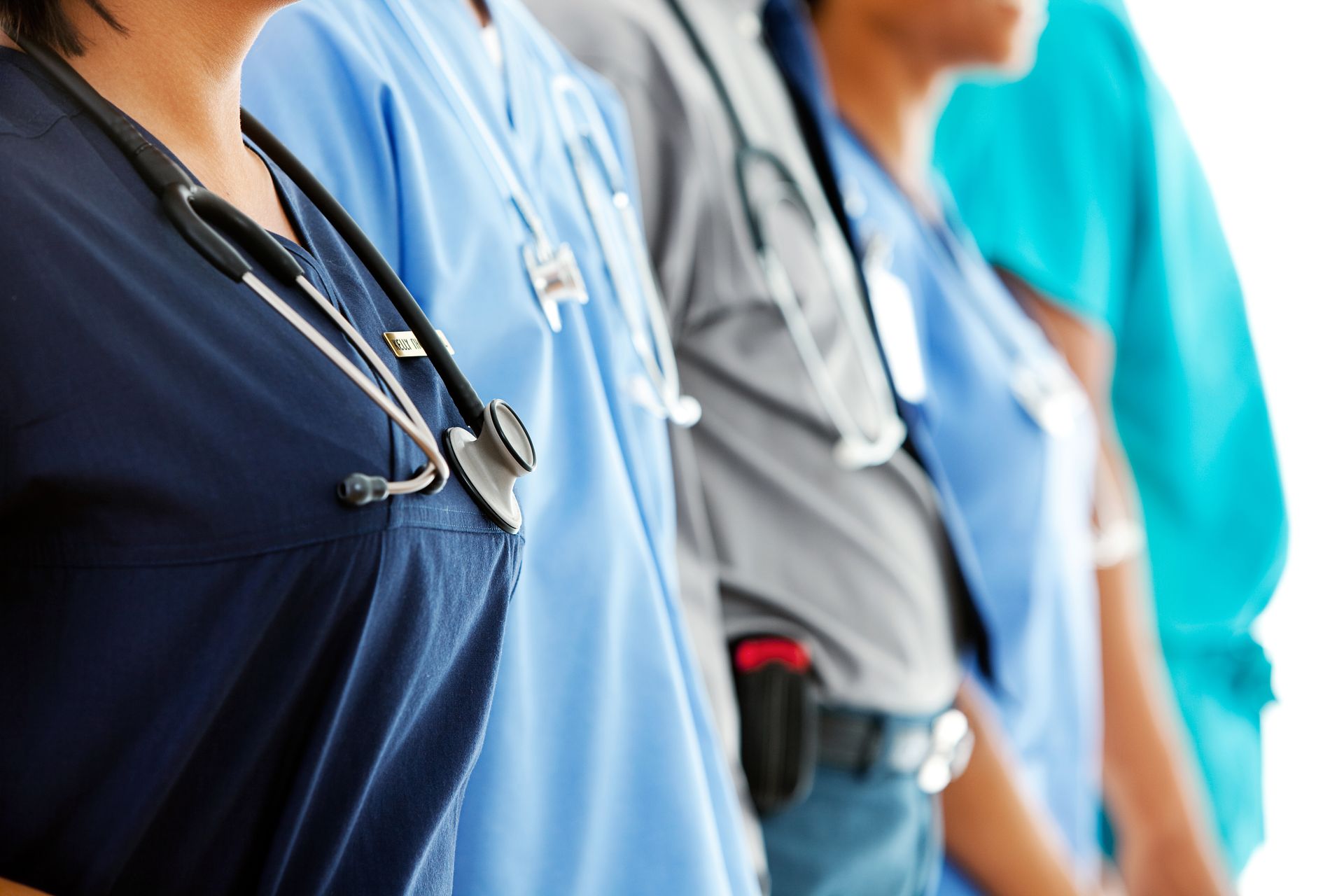 Medical professionals in various scrubs and stethoscopes, standing in a line.