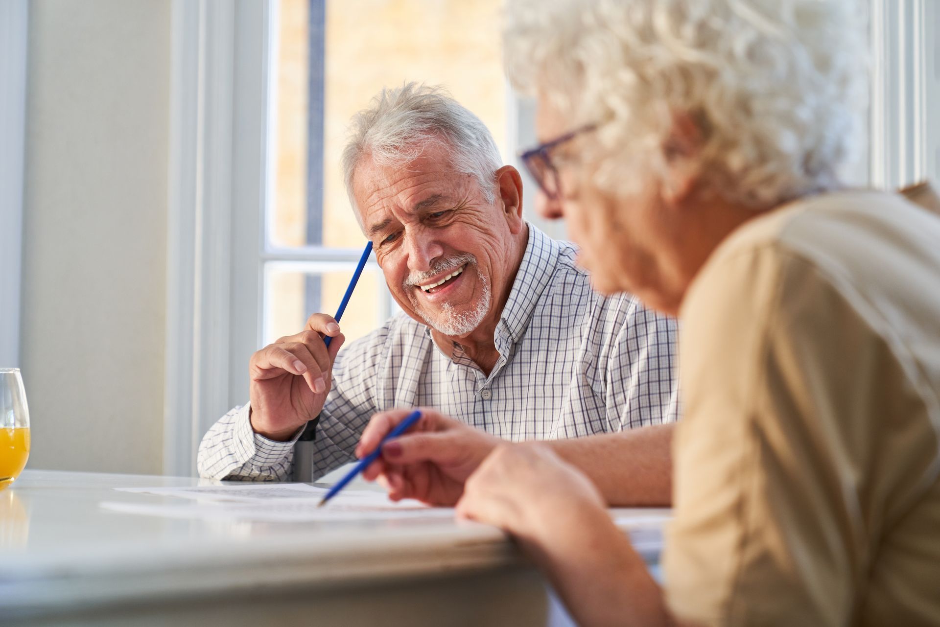 Smiling man and woman reviewing papers, possibly working together at a table.