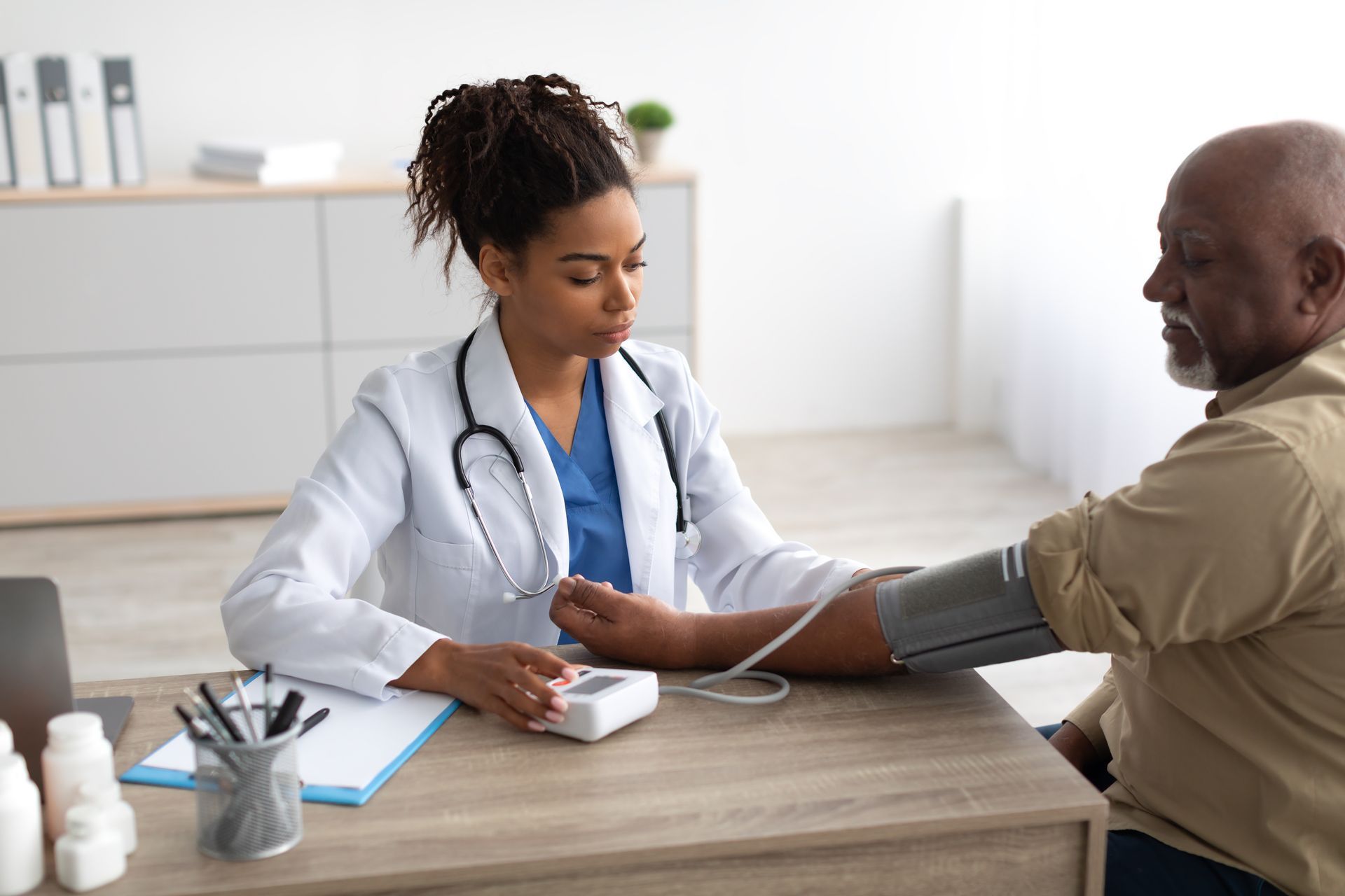 Doctor taking a patient's blood pressure in an office.