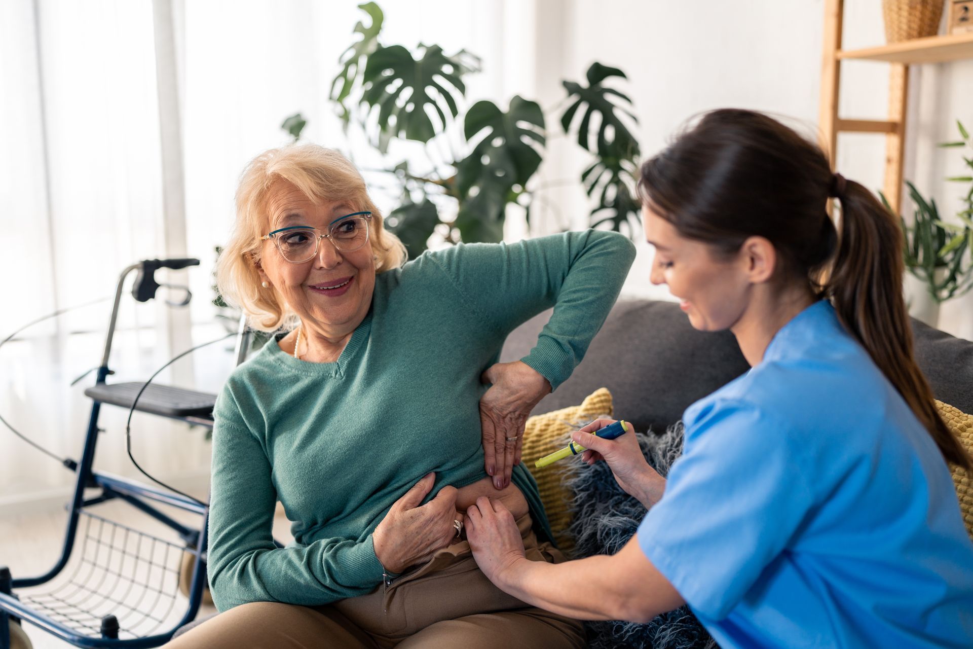 Caregiver administering an injection to a person's abdomen, indoors.