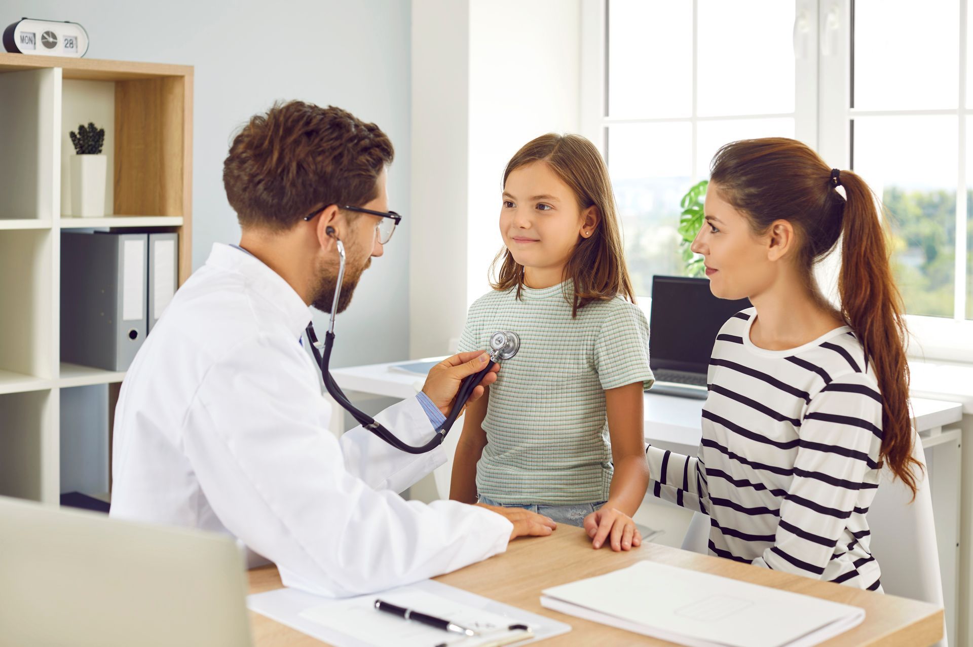 Doctor using a stethoscope to take a patient's blood pressure with an automated cuff on the arm.