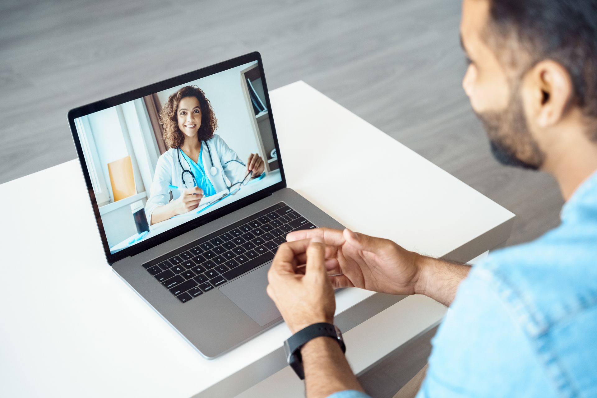 Man having a telehealth appointment with a doctor via laptop.