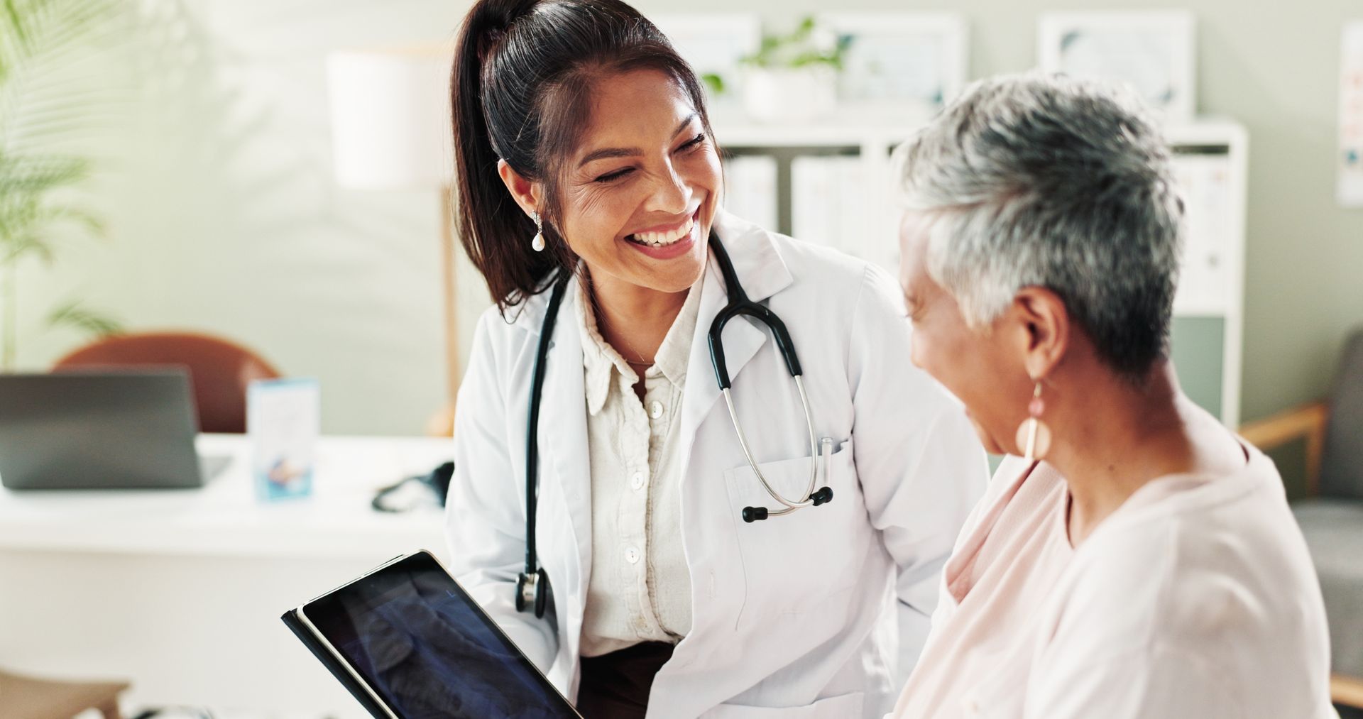 Doctor smiles at patient, pointing at a medical chart in an office.
