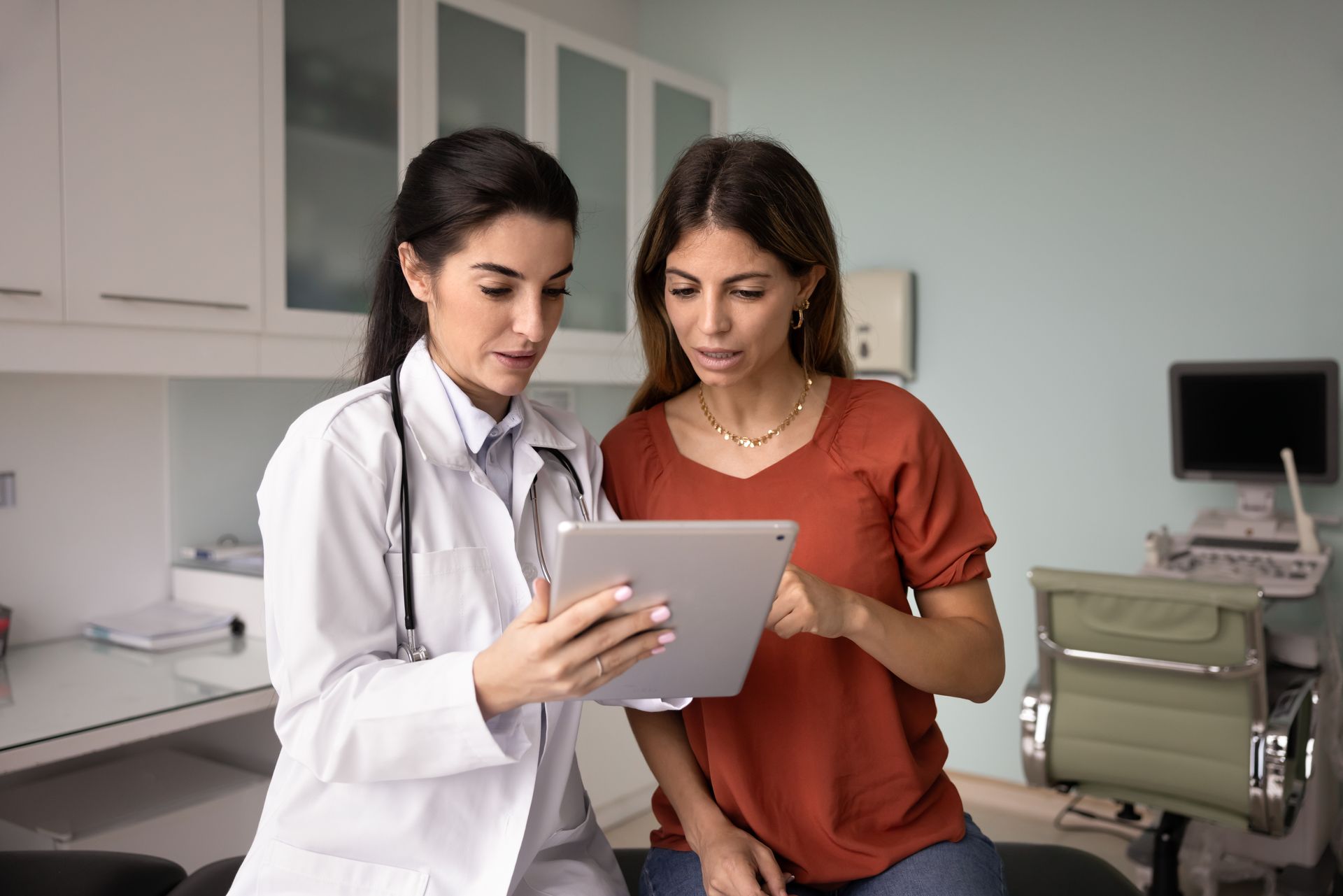 Doctor and patient looking at tablet in a medical office.