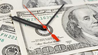 Couple walking, hugging, with suitcase outside building.