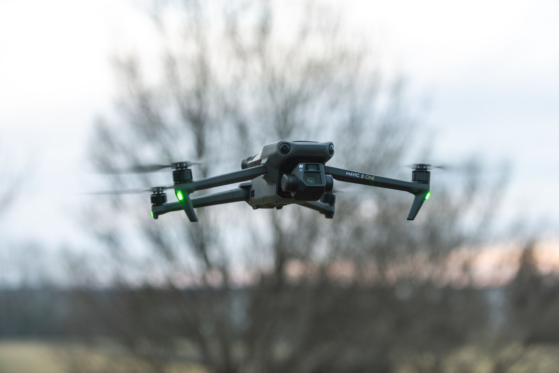 a drone is flying over a field with trees in the background .