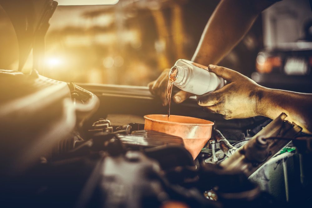 A Close Up Of A Person Pouring Oil Into A Car Engine — Fase Automotive In Sunset, QLD