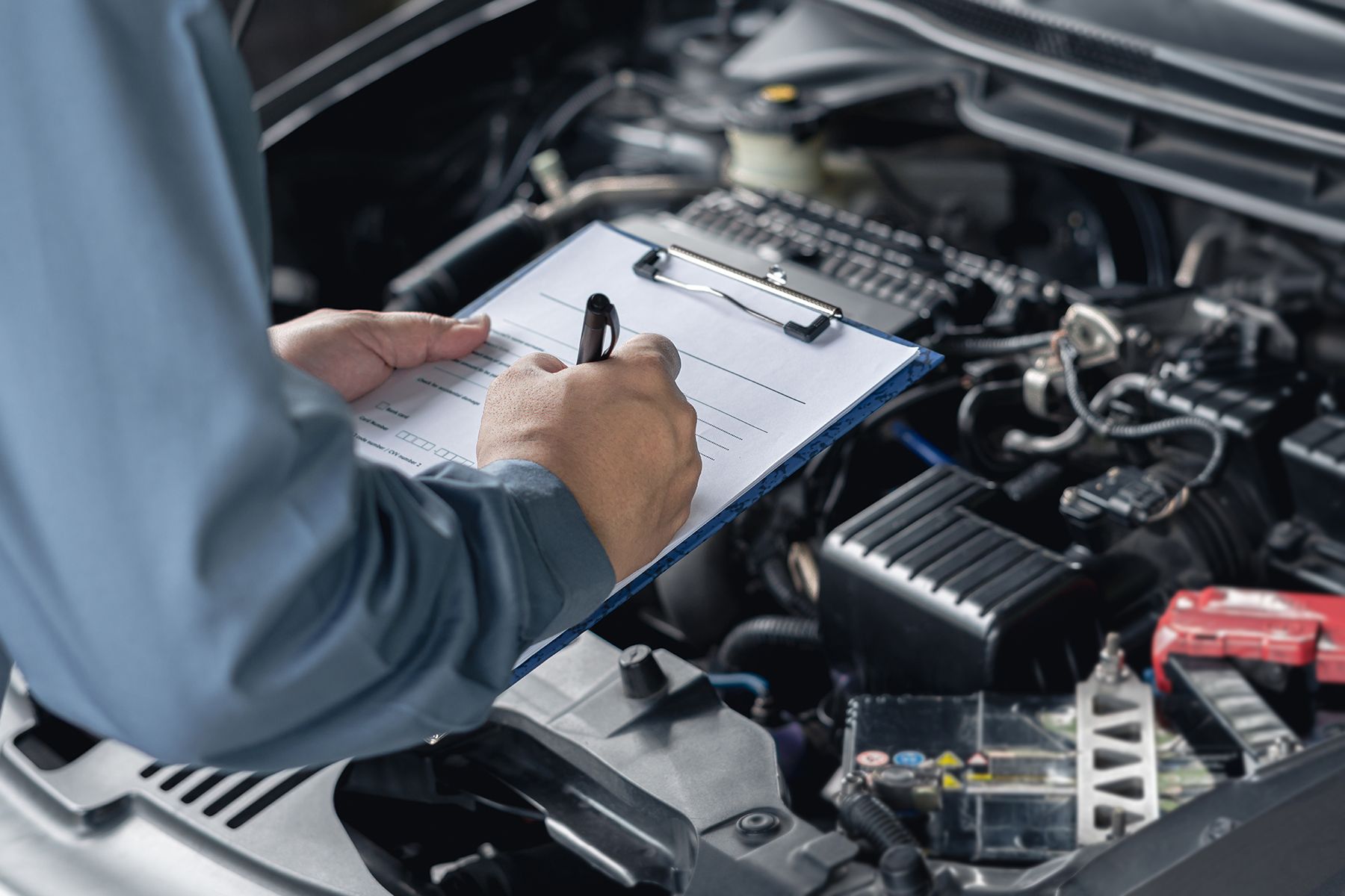 A Mechanic Is Writing On A Clipboard While Working On A Car — Fase Automotive In Sunset, QLD