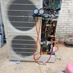 An air conditioning unit with gauges connected, wires exposed, on a concrete surface.