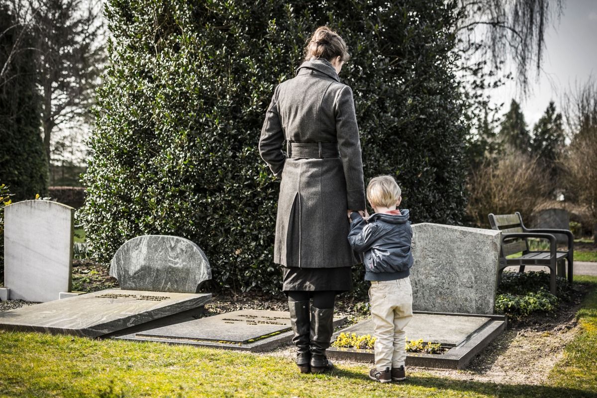 Woman and child at gravesite, looking at headstones.