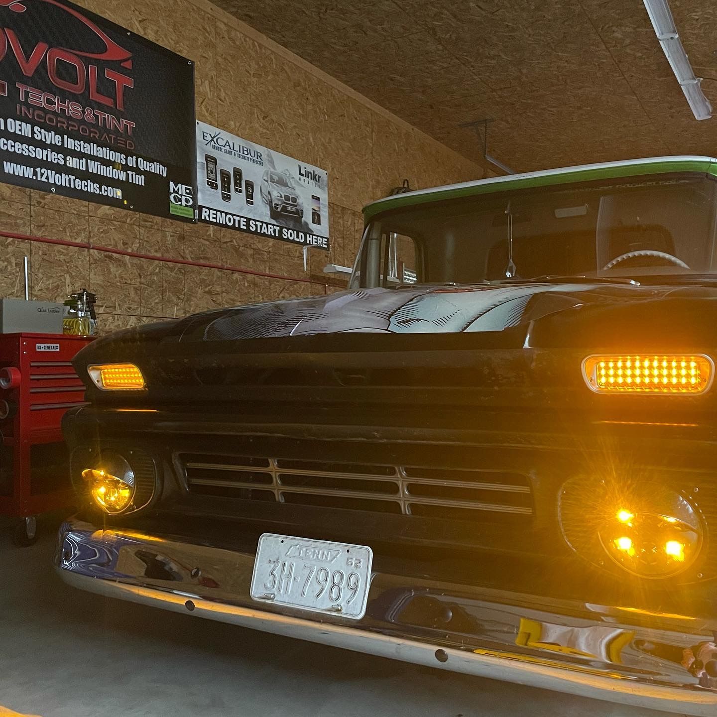 A truck is parked in a garage under a sign that says volt