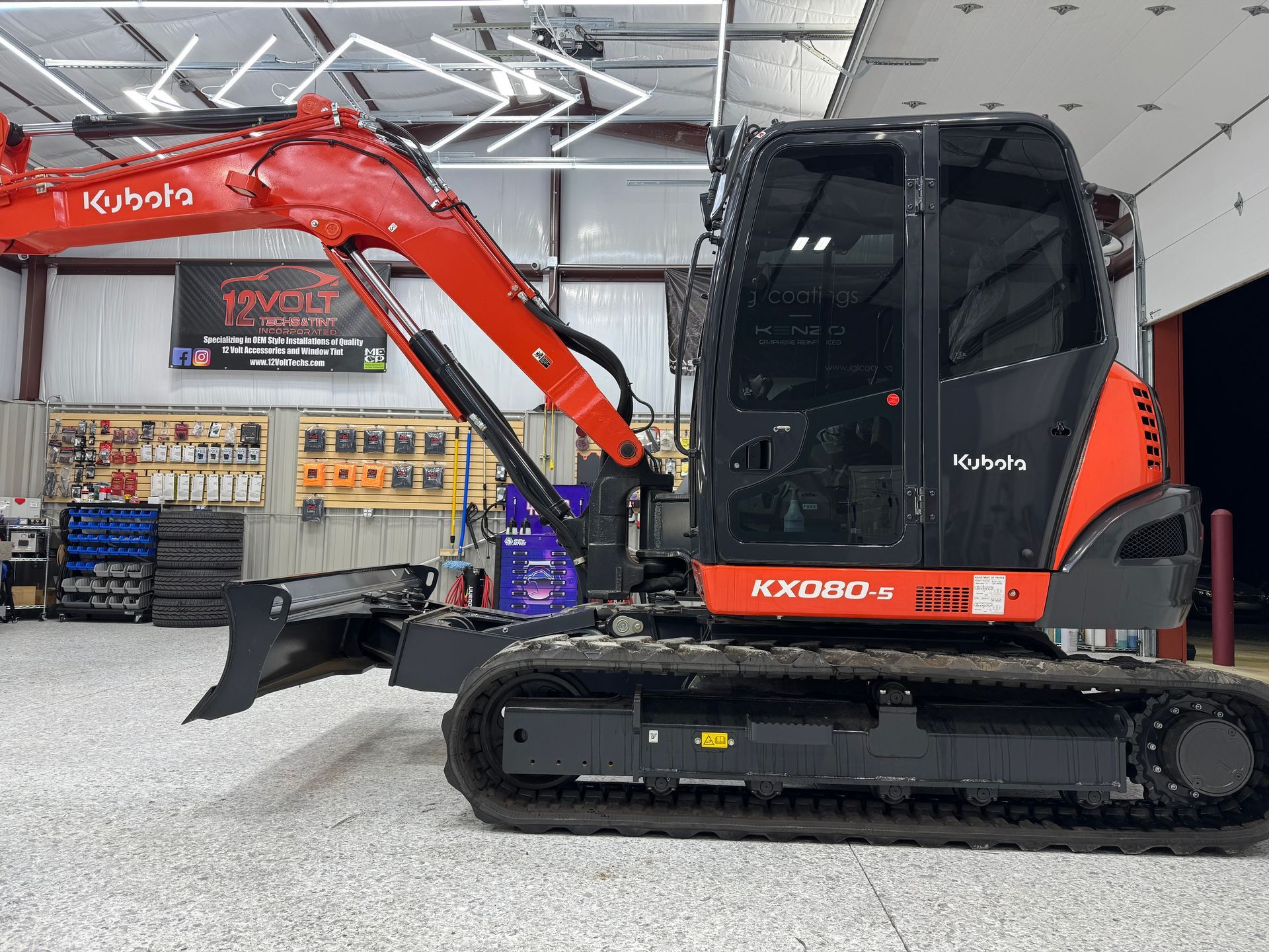A red and black excavator is parked in a garage.