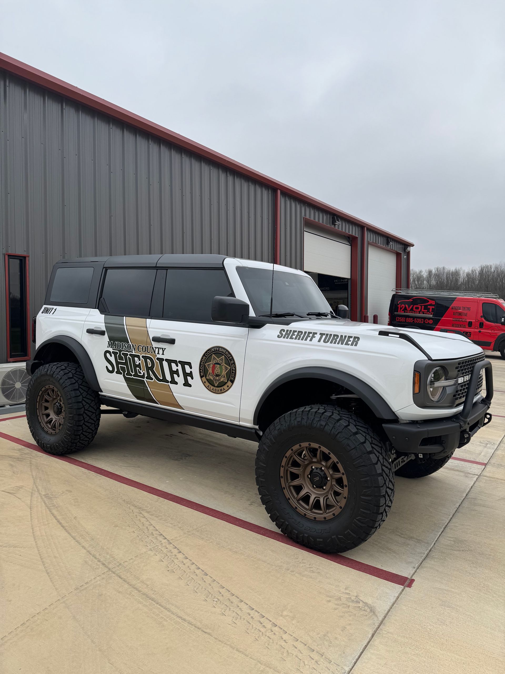 A red ford bronco is parked in front of a building.