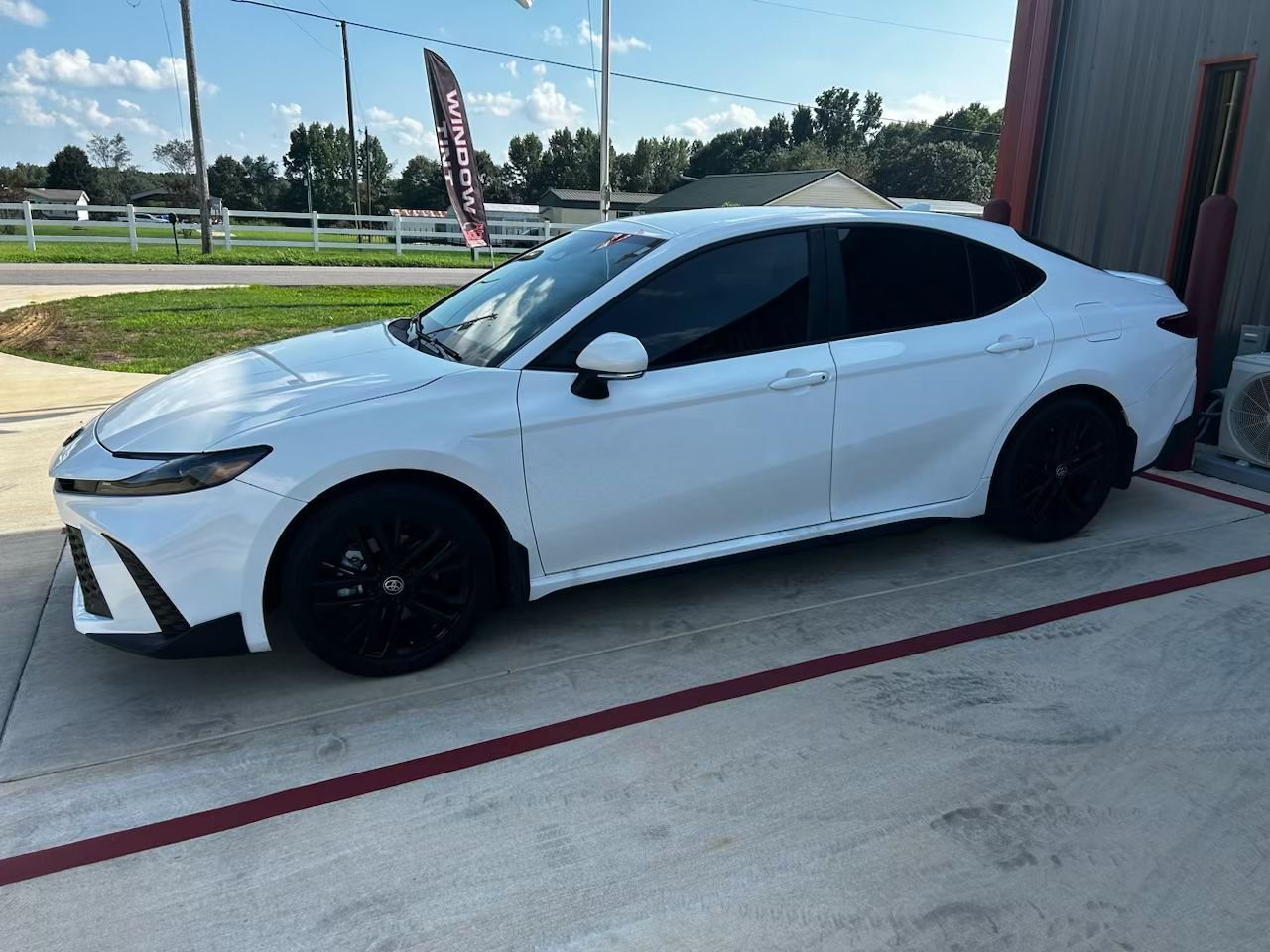 A white toyota camry is parked in a parking lot.
