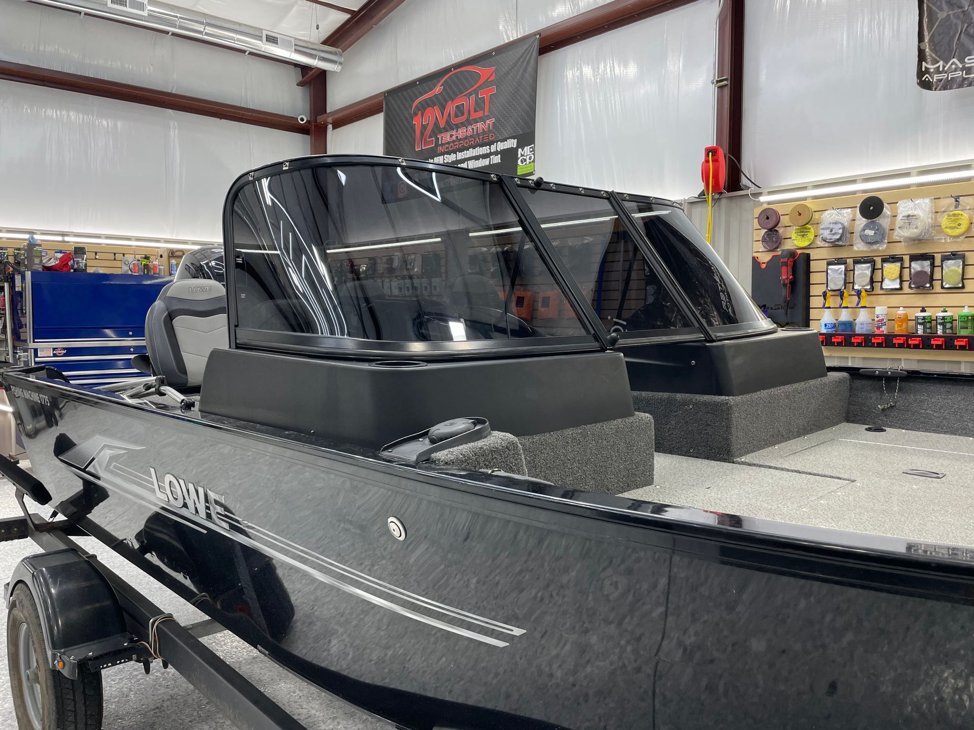 A black boat is sitting on a trailer in a garage.