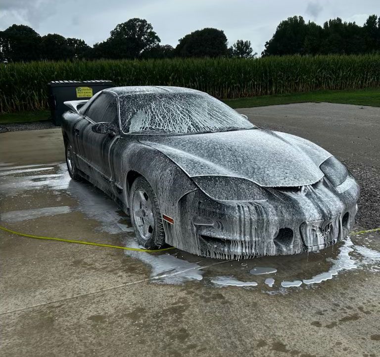 A car is covered in foam and is being washed