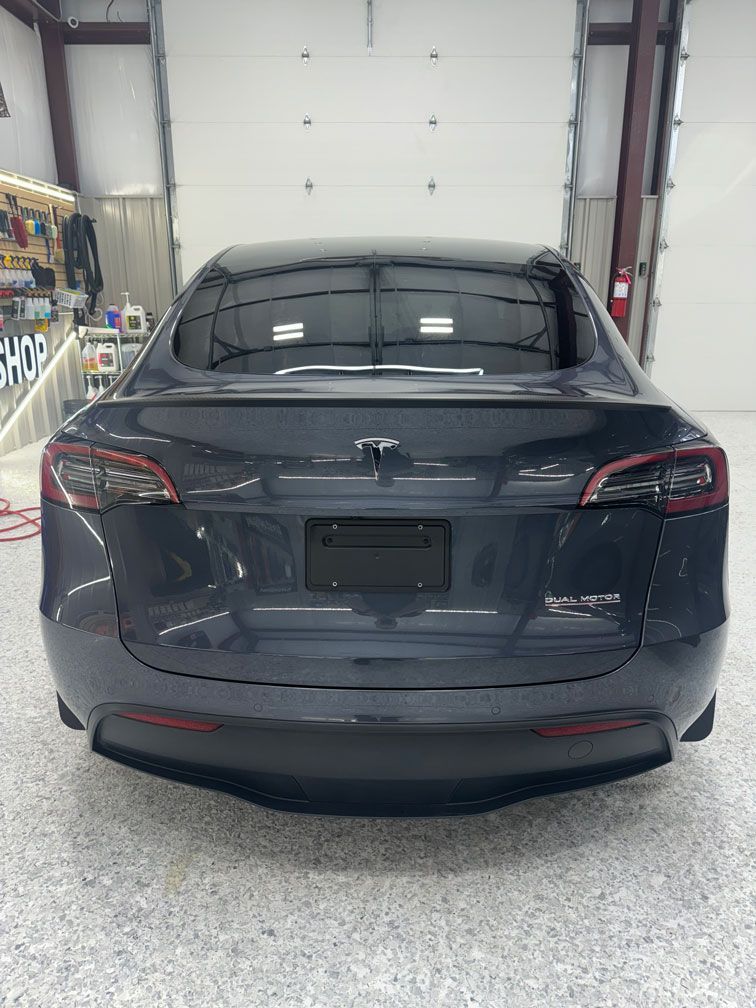 The back of a tesla model 3 is shown in a garage.