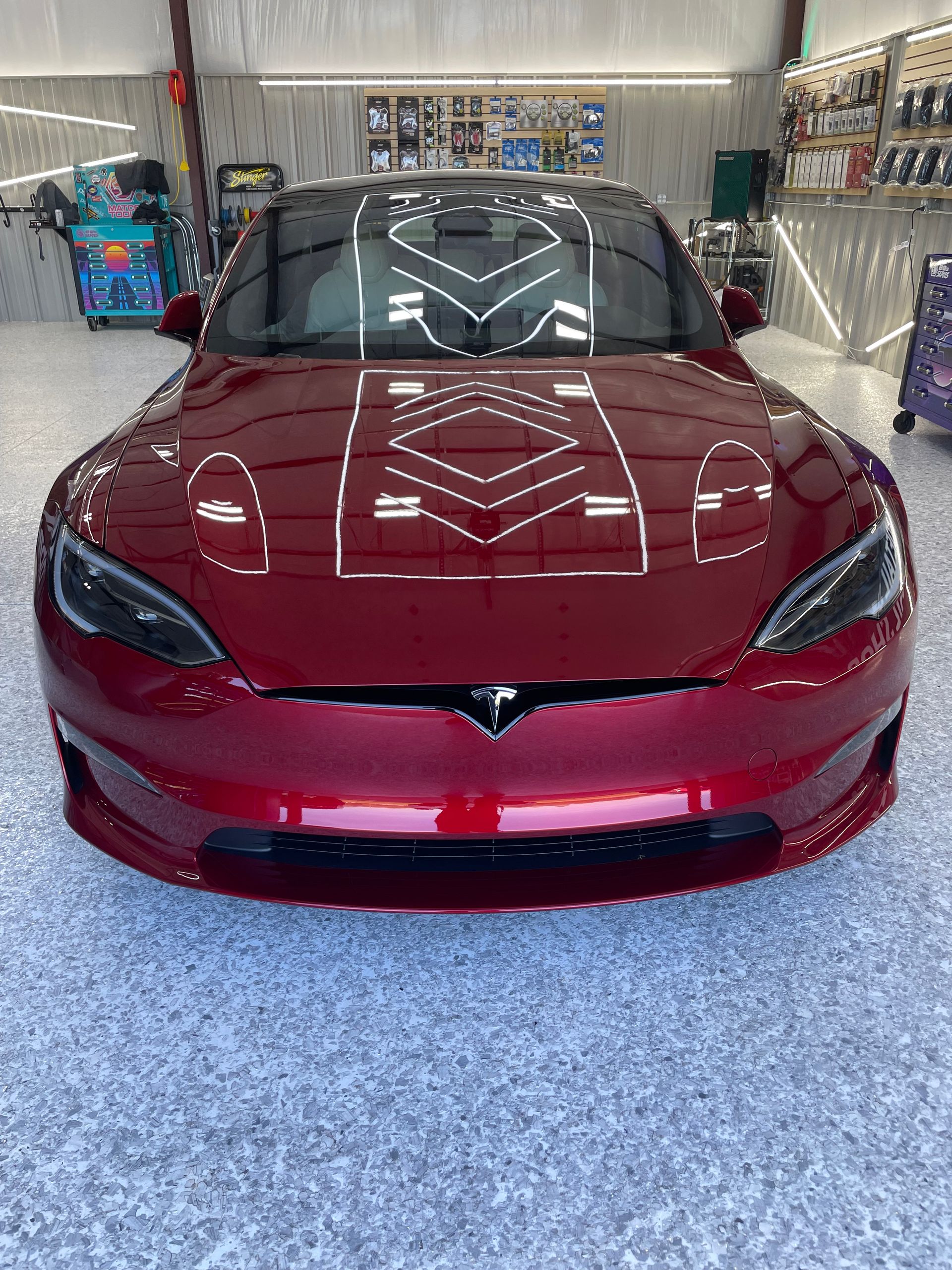 A red tesla model s is parked in a garage.